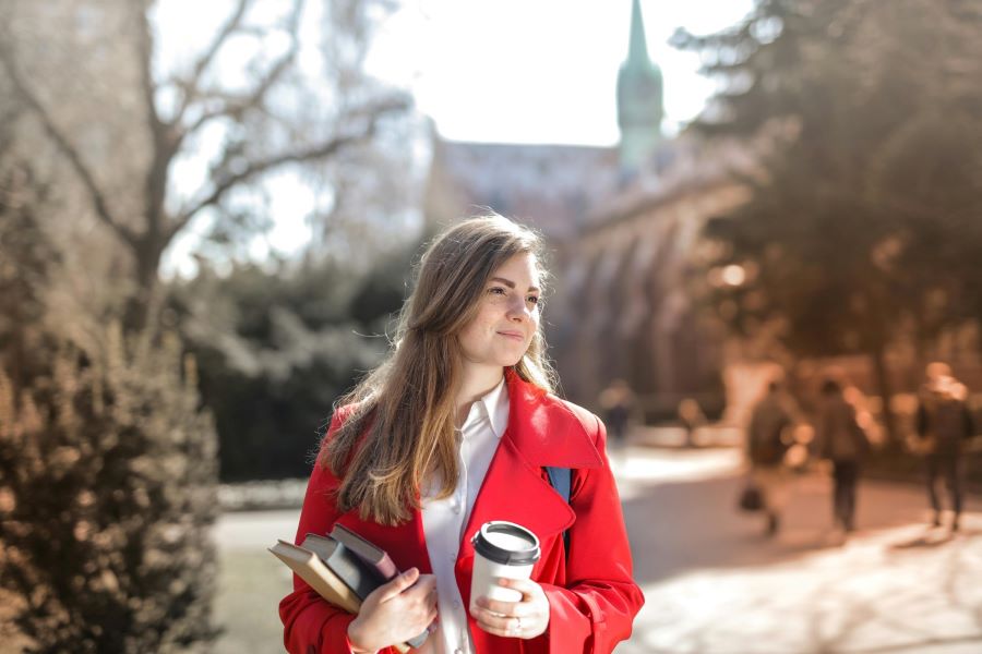 student with coffee and books on campus