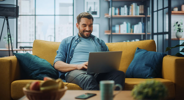 man on couch using laptop