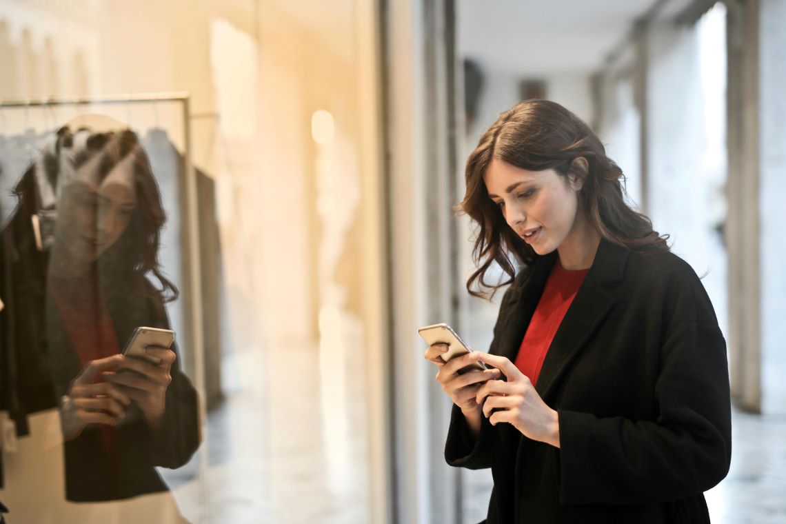 woman looking at credit card balance outside a store