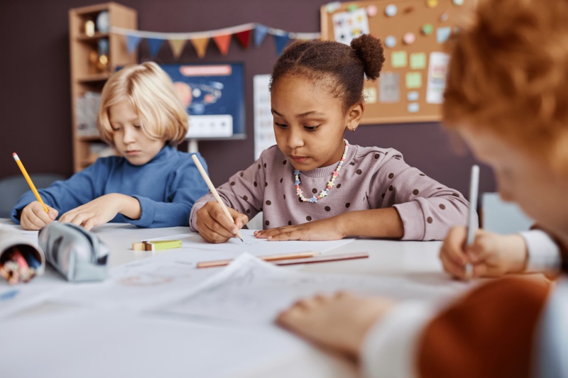 Children Writing At A School Table Uncropped